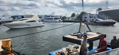 Crane handling a floating work platform beside a yacht