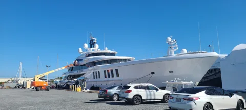 Extended aerial lift positioned beside a yacht bow for polishing
