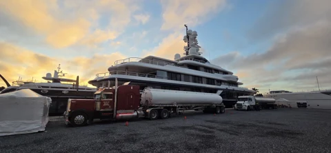 Fuel tanker alongside a yacht beneath a sunset sky