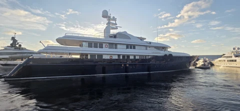 Dark-hulled yacht alongside the dock in evening light
