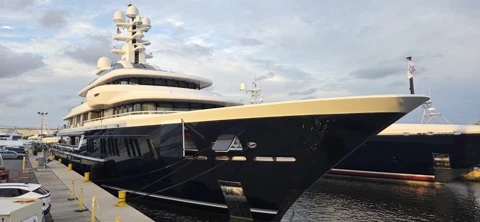 Dark-hulled superyacht viewed from the bow at the yard